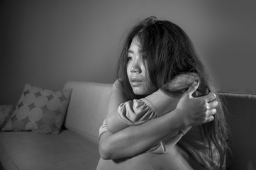 young sad and depressed Asian Japanese woman at home sofa couch crying desperate and helpless...