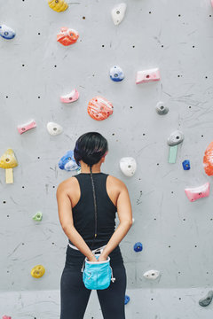 Female climber taking chalk powder from sack on her waist