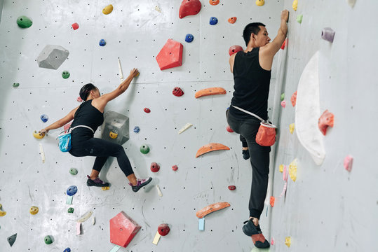 Sporty couple enjoying bouldering in climbing center