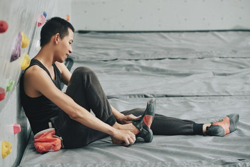 Smiling young climber wearing professional shoes for bouldering