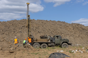 Drilling machine, ecologist and soil samples at the construction site