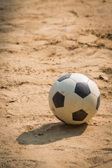 Fototapeta na wymiar Classic black and white football soccer ball on sand