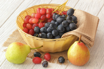Red and blue grapes with pears on white wooden table