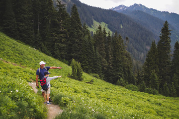 a grandfather and grandson hiking through a lush green alpine meadow
