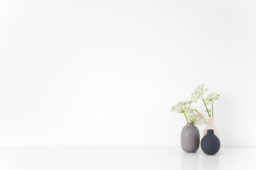 Elegant indoor interior. Gray, black and white vases with herbal gerard bouquet on table on white background. Cute soft home decor. poster Mockup