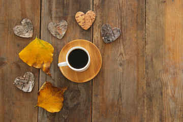 top view image of coffee cup over wooden table and dry autumn leaves.