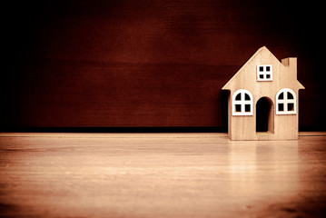 The symbol of the house stands on a brown wooden background 