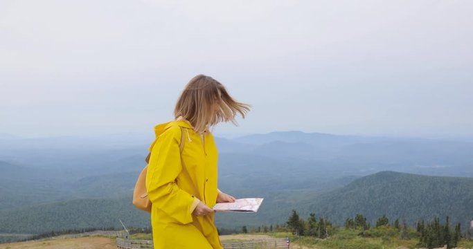 Young female Hiker looking at map from mountain top