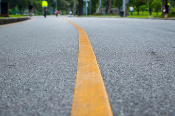 Close up of yellow line  on the public park with people exercise and cycling for good health