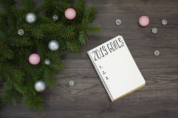 Fototapeta na wymiar 2019 New Year's goals. Notebook and christmas tree on wooden background