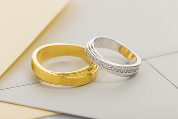 Gold and silver wedding rings on envelope background