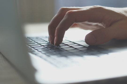 blurred image of male hand typing on laptop keyboard.close up