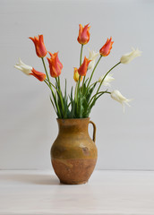 Bouquet of white and orange tulips and lilac in  vase  on white background