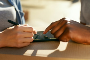 Package Delivery. Close Up Hand Signing On Phone On Box