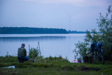 Fisherman on the shore of evening lake
