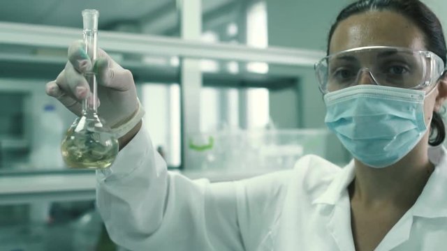 Beautiful lab technician strips the flask with a chemical fluid