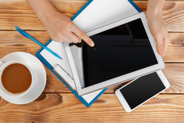 Girl hands with digital tablet and cup of coffee on a wooden table