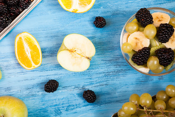 Sliced fruits and berried top view on blue wooden background. A wooden table with fresh tropical fruits. Healthy nature freshness mix of fruits