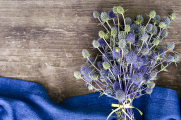Field eryngium with blue textiles on a wooden table