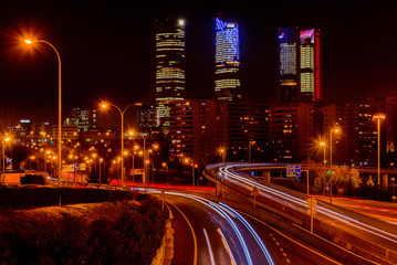 Fototapeta na wymiar Night long exposure photography at M30 highway with Madrid skyline (Four towers business area) as background, Spain