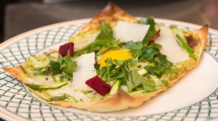 Open faced spring vegetable lasagna with an egg in the center.