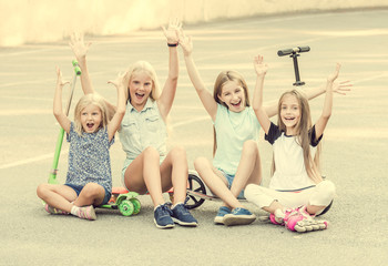 Little girls smiling sitting on the ground with raised hands