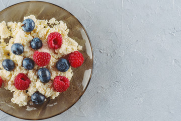 Cottage cheese with fresh raspberries and blueberries in a plate for a healthy breakfast with ripe berries. A natural healthy product.