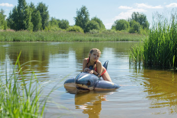 girl swimming in the river on an inflatable shark