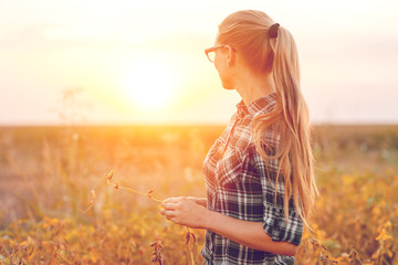 Portrait of young female farmer standing in soybean field.	