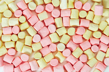Background from yellow and pink mini marshmallow. Sweet zephyr. Fon from marshmallows close up. Top view.