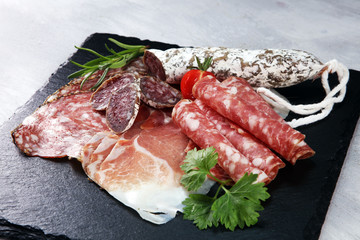 Food tray with delicious salami, ham,  fresh sausages and herbs. Meat platter with selection