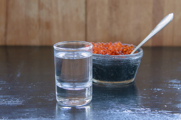 Vodka with black and red caviar on a black background