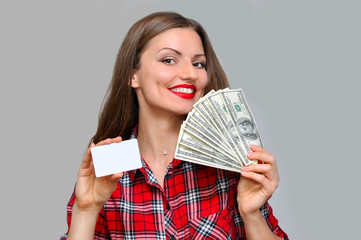 Beautiful woman in a red shirt enjoys a large amount of money in her hand and a credit card