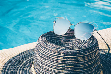 Women's hat and sunglasses near the pool on vacation