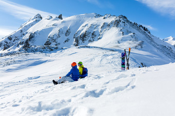 Naklejka na ściany i meble snowboarder and skiier sitting on snow and see at mountains