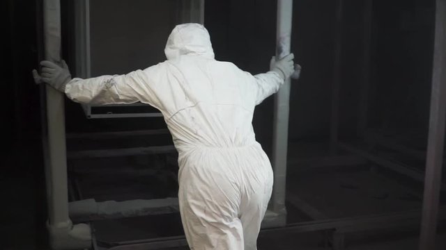 Worker puts a new object in the paint booth for painting. Clip. Painting booth at the factory. Tradesman working in a painting booth, Man paining industrial equipment in a factory