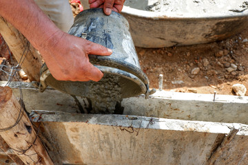 Worker leveling concrete poured from mixer on construction site