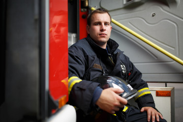 Photo of fireman with helmet in hands sitting in fire engine