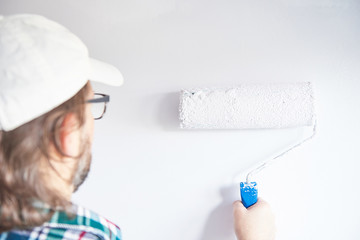 Man painting wall in white colour
