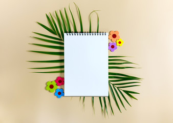 Notebook for mock up with green leaves of palm tree on bright background