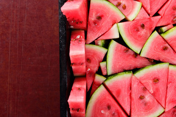 Pattern of watermelon slices. Pieces of ripe watermelon in old metal dishes. Red fruit with...