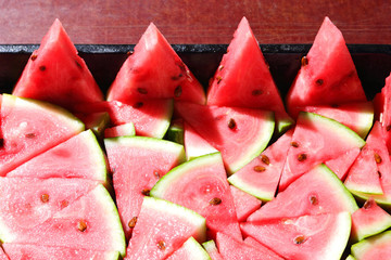 Pattern of watermelon slices. Pieces of ripe watermelon in old metal dishes. Red fruit with...
