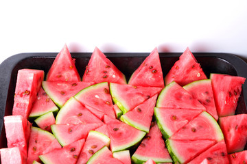 Pattern of watermelon slices. Pieces of ripe watermelon in old metal dishes. Red fruit with...