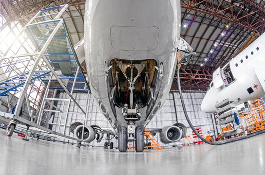Aviation hangar with airplane, close-up front landing gear of the airplane landing gear on maintenance repair.
