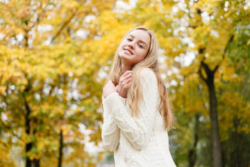 season and people concept - beautiful happy young woman having fun with leaves in autumn park