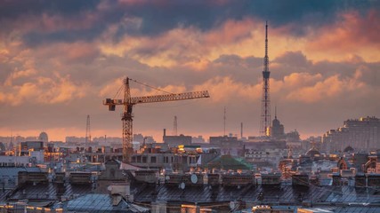 Construction crane and TV Tower over rooftops cityscape of St Petersburg, Russia, epic sunset clouds moving in background. 4K UHD Timelapse.