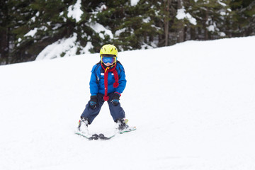 Fototapeta na wymiar Young child, skiing on snow slope in ski resort in Austria