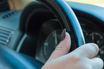 Female holding black steering wheel of a car close up
