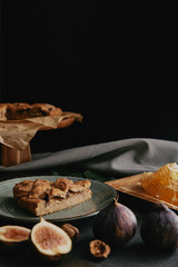 close up view of baked pie, beeswax and figs arranged on dark surface