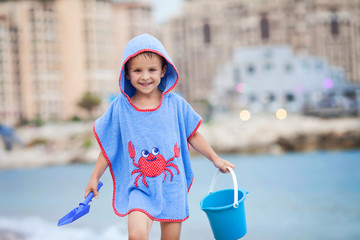 Cute little preschooler boy, playing in the sand on the beach with beach toys